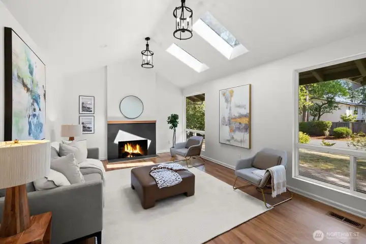 The living room shines with more skylights, where the wood fireplace, vaulted ceiling, and large window come together beautifully.