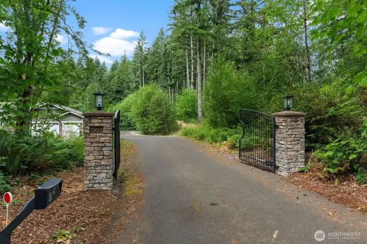 Enjoy the privacy of a gated entrance leading to this beautifully maintained home with a spacious driveway, welcoming covered entry, and picturesque wooded surroundings.