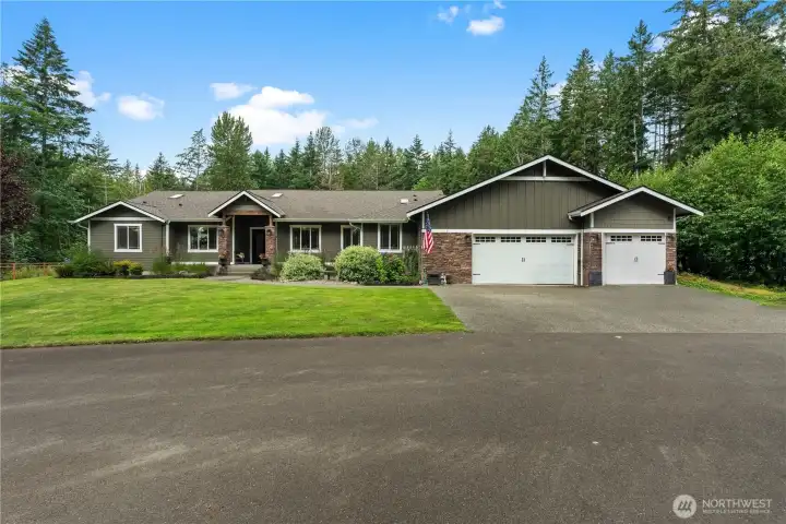 Front exterior features a covered porch, stone details, and a landscaped walkway leading to the double-door entrance.