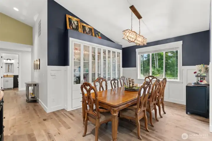 The spacious dining room features built-in cabinetry, a statement light fixture, and a large picture window overlooking the surrounding greenery