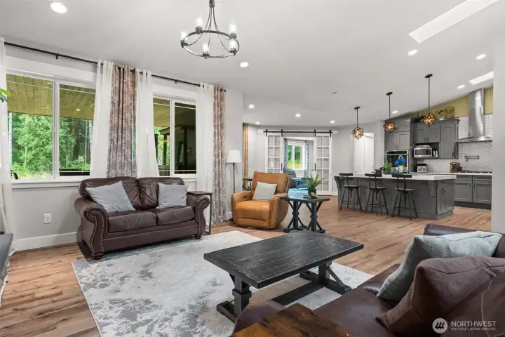 The open great room flows naturally into the kitchen and offers large windows overlooking the covered patio and surrounding trees.