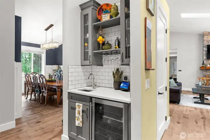 Designed for entertaining, the beverage bar features a sink, beverage refrigerator, glass storage, and built-in cabinetry for added convenience.