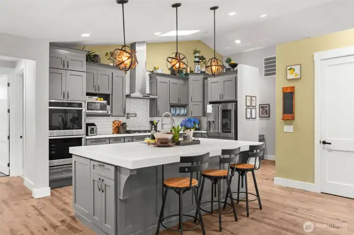 The thoughtfully designed kitchen features an oversized island with seating, custom cabinetry, stainless steel appliances, and generous prep space.