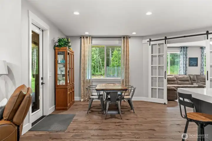 The dining area features large windows overlooking the backyard, convenient access to the covered patio, and sliding barn doors leading to the adjacent flex room.