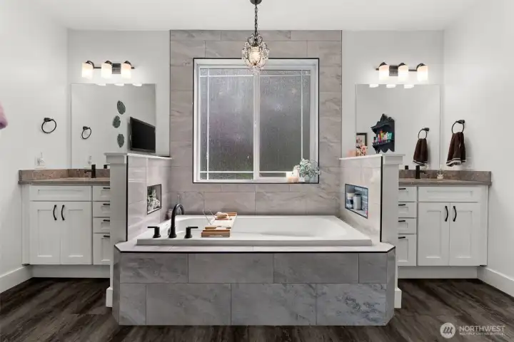 Spacious primary bath features a soaking tub, walk-in shower, dual vanities, tiled finishes, built-in storage niches, generous cabinetry, and a thoughtfully designed layout for everyday comfort.