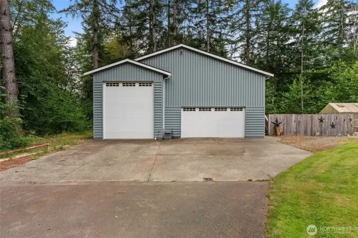 Detached shop features oversized RV-height garage door, additional double garage bays, and a spacious concrete driveway.