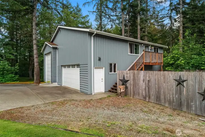 Detached shop features oversized RV-height access, dual garage bays, and an upper-level ADU with a private exterior entrance and deck.