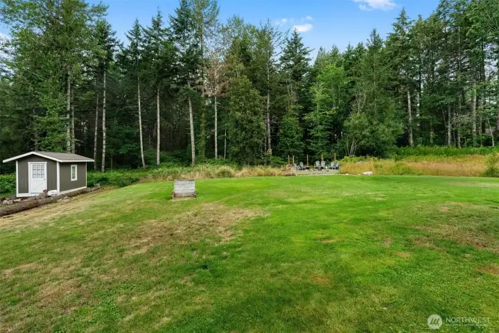 Level backyard provides room for recreation, a storage shed, and an established fire pit area for outdoor enjoyment.
