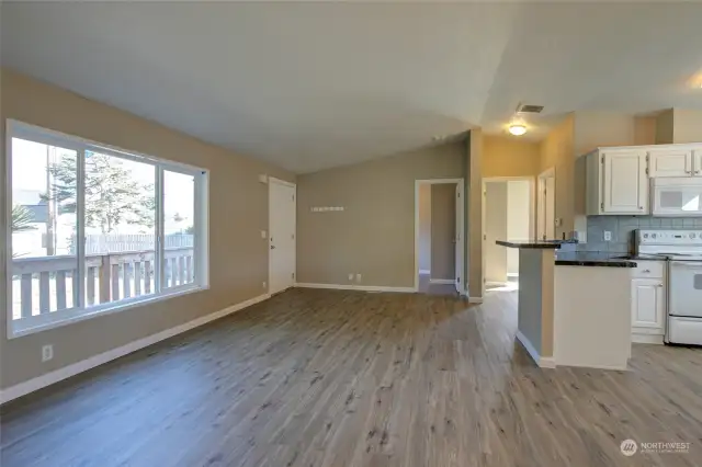 Large living area with eating bar at the kitchen peninsula, in addition to space for a dining table near the utility room.