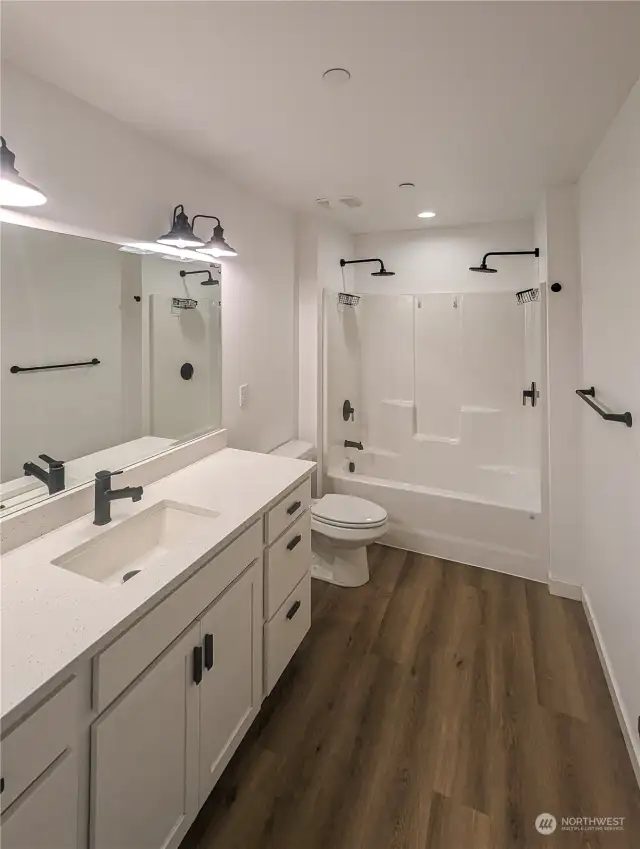 Large vanity with quartz countertops and spacious bathroom with double shower heads