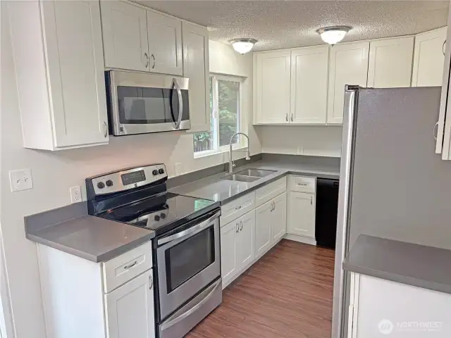 Kitchen with stainless-steel appliances in this updated split-level at 16312 127th Pl SE, Renton—opens to the dining area; new flooring and fresh paint in Cascade 98058.