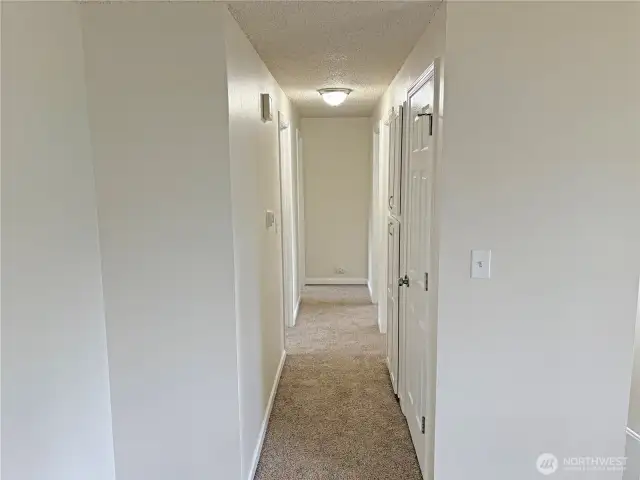 Hallway leading to bedrooms and a full bathroom in this updated split-level at 16312 127th Pl SE, Renton—new flooring, fresh paint, and a functional layout in the Cascade neighborhood 98058.