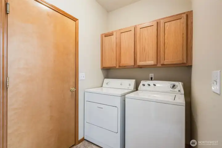 The utility room offers extra storage above the washer and dryer. It's conveniently located next to the garage and kitchen.