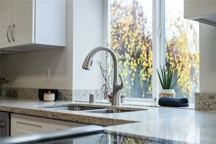 A generous window over the kitchen sink invites light and spaciousness into the kitchen.