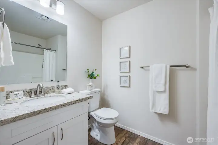 Features of the primary suite bathroom include an updated vanity with quartz countertop, new toilet, new mirror, new light fixture, and new flooring.
