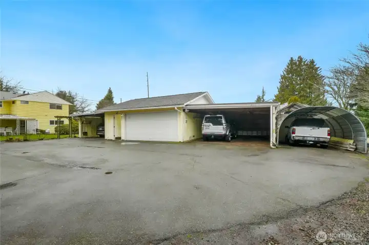 Rear of home with 2 car carports on both right and left of oversized 2 car garage, plus another covered parking area and covered porch area on far left of photo.