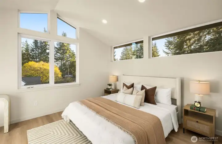 Serene primary bedroom with vaulted ceilings and large windows overlooking the neighborhood.