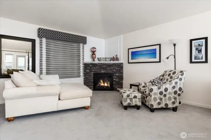 As you enter the Primary Ensuite, you are greeted by a comfortable sitting area and a propane gas fireplace with stone surround. Custom curtains and plush carpeting.