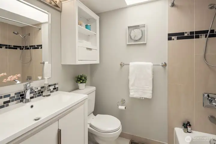 A shared hall bath with updated vanity and large skylight