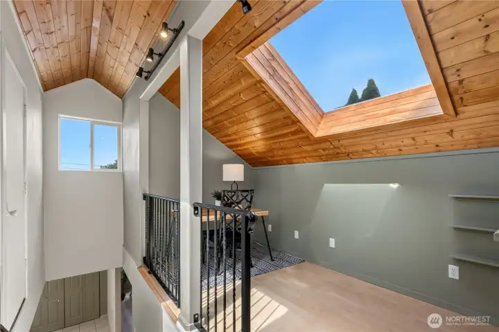 Large skylight fills the loft with abundant natural light while the warm wood ceiling creates a welcoming atmosphere. Large skylight fills the loft with abundant natural light while the warm wood ceiling creates a welcoming atmosphere.