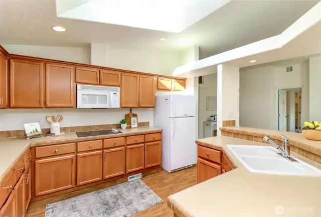 Large kitchen with white refrigerator, dishwasher, microwave and oven.