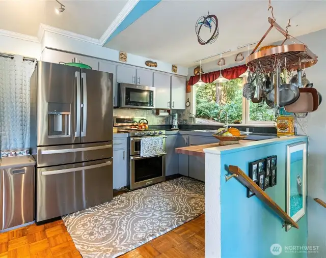 Open kitchen with stainless steel appliances and bay window.