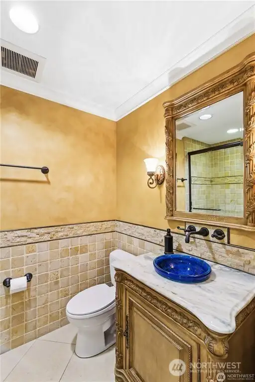 Powder room utilizing only the best in materials/fixtures with a Robert Jones Custom hand blown glass sink. Tumbled marble wrapped tile shower. Golden Venetian Plaster walls.