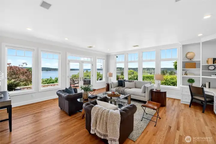 Front room with sweeping views of the water. French doors open out to patio. Notice the newly refinished hardwood floors, and built-ins to the right. Large, energy efficient windows fill each room with natural light and stunning water and mountain views. Sunsets, sunrises and moonrises are spectacular.
