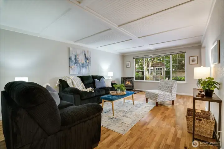 Hardwood floors and shiplap ceilings add warmth and character, while a large window fills the living room with natural light and views of the backyard Hardwood floors and shiplap ceilings add warmth and character, while a large window fills the living room with natural light and views of the backyard