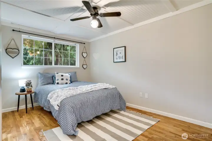 A large window fills the second bedroom with natural light, while a ceiling fan helps keep the space comfortable. A large window fills the second bedroom with natural light, while a ceiling fan helps keep the space comfortable.