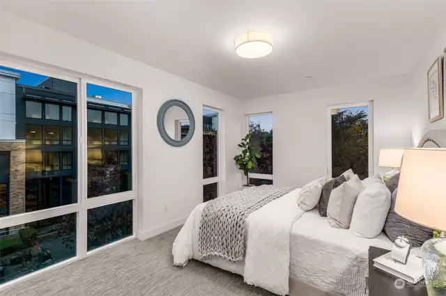 Step into the cozy elegance of this sunlit bedroom. Expansive windows frame serene views while filling the space with natural light, creating the perfect relaxing ambiance.