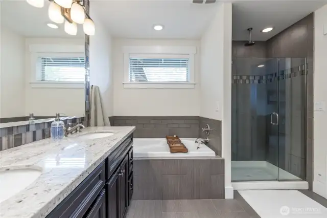 Elegant primary suite with modern tile and dual sinks