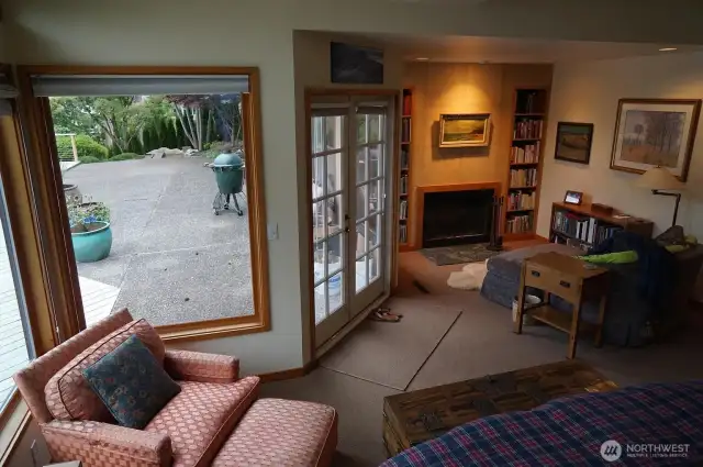 Another view of the primary suite, with french doors opening to the spacious back deck, and another fireplace and cozy reading area.