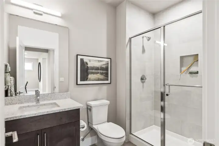 Main level bathroom with large walk-in shower. Photo is representational. Actual home is under construction and materials, colors, and finishes will vary. See site agent for details.