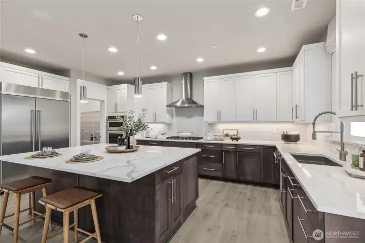 Gourmet kitchen with large center island, loads of cabinets, built-in 48" fridge, gas cooktop, in-wall oven, and microwave.  Photo is representational. Actual home is under construction and materials, colors, and finishes will vary. See site agent for details.