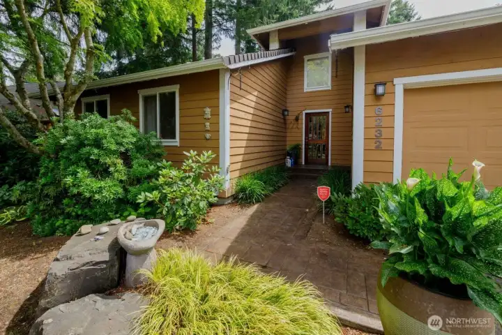 Mature landscaping surrounds this home - in the front find plantings, cedars, and slate patio and stairs