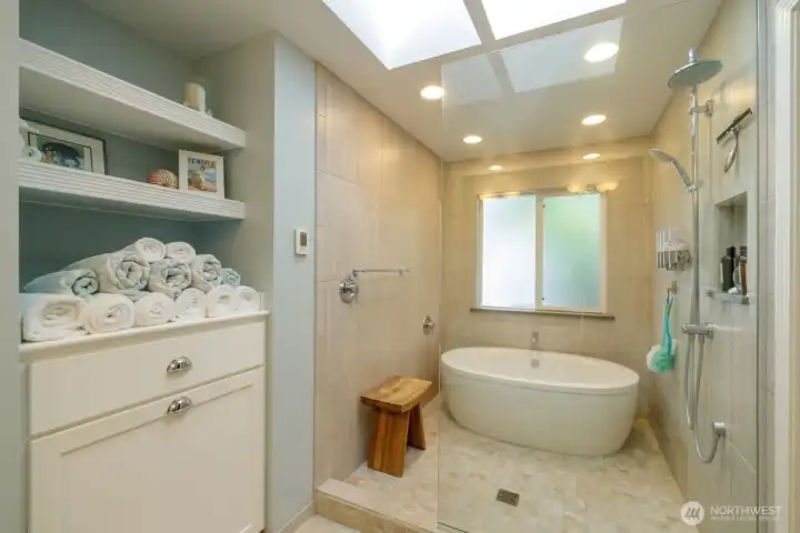 Ensuite bathroom with wet room bathtub and shower, towel storage, double sink, and private water closet.