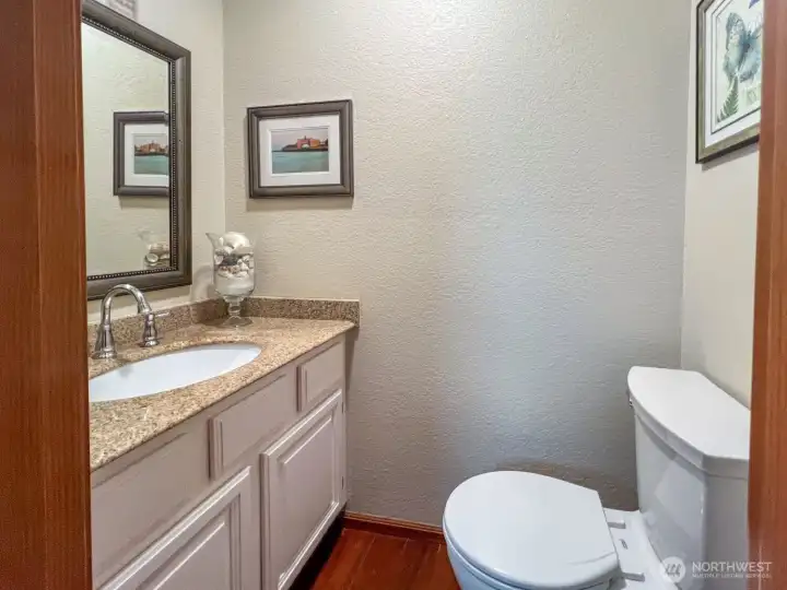 Half-bath near living room with updated granite countertops.