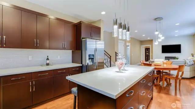 Gourmet kitchen with oversized island, quartz countertops, with hardwood floors throughout, opens to breakfast nook & family room with gas fireplace.