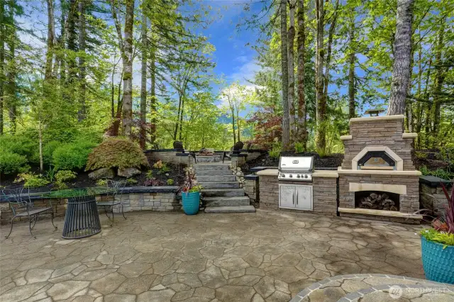 Enjoy your outside Wood Burning Pizza oven as you entertain. Stone Stairs to a second round patio with firepit  overlooking the River beyond.