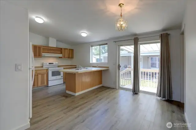 Open concept kitchen and dining area with new flooring, cabinet doors and newer range/oven and fridge.