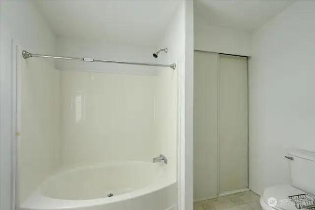 Primary bath with large soaking tub and linen closet.