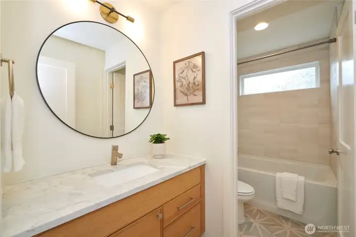 An elegant full bathroom finishes off the entry level. Note the quartz countertops, undermount sink, tile flooring, beautiful tile tub surround and West Elm lighting package. This is not your "cookie cutter" townhome!