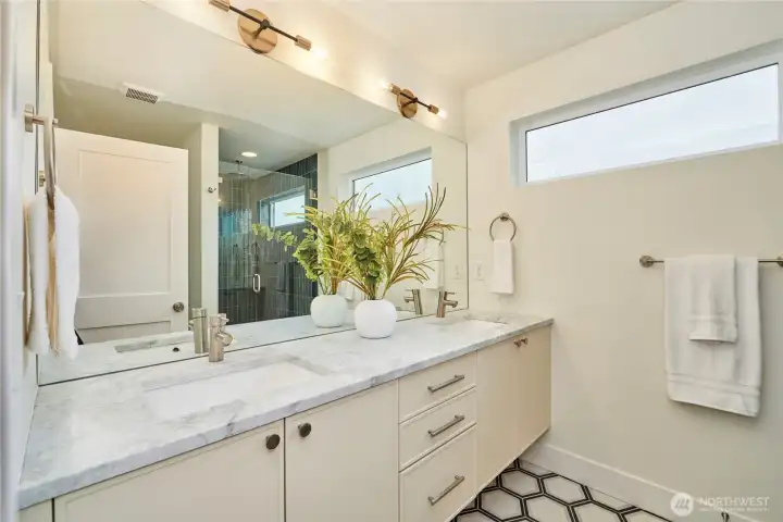 A look at the "spa-like" primary bathroom with quartz countertops, 2 undermount sinks, Grohe faucets, tile floor, West Elm lighting and tile shower surround with both rainfall and hand held shower heads.