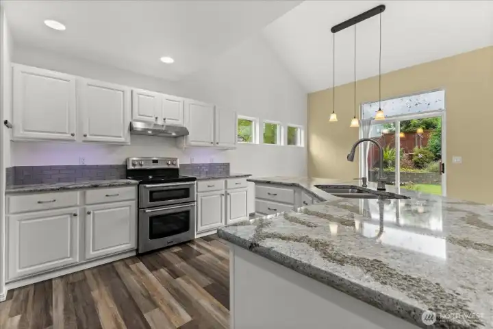 Kitchen w/ timeless white cabinets, slab stone countertops, glass backsplash & double oven.
