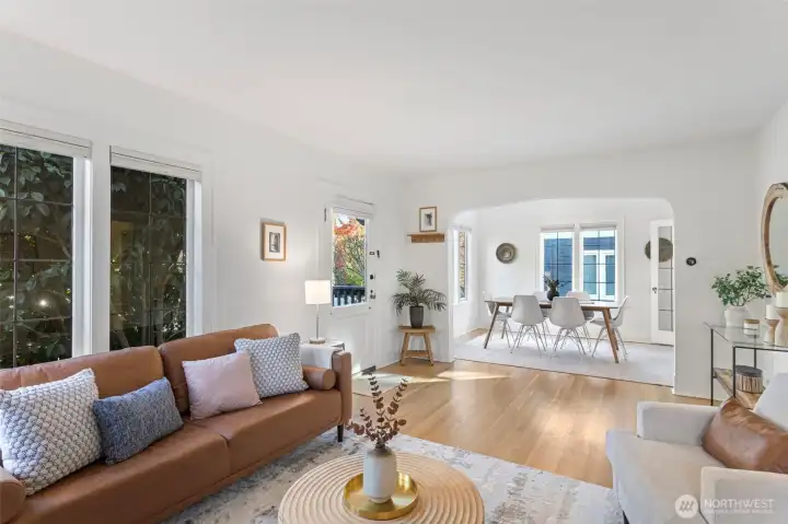Step through the front door into a light-filled living and dining  space where leaded glass windows catch the morning sun. Original hardwood floors, a graceful  archway, and a wood-burning fireplace set the tone—beautifully blending 1925 Tudor  character with everyday comfort and style.