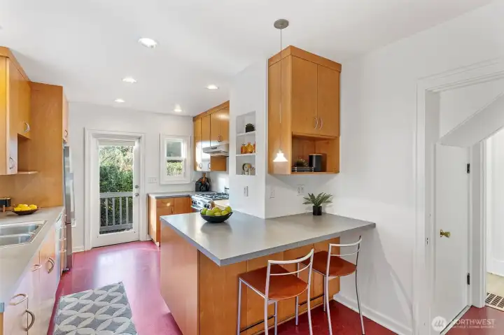 A KITCHEN WITH CHARACTER Full of natural light and classic charm, the kitchen features  Marmoleum flooring, glass-fronted cabinets, and both a leaded glass door to the dining room  and a glass-paned door to the backyard. Modern updates include a Bosch dishwasher, Fisher &  Paykel fridge, Décor gas range, and Allure hood vent. Step right out to the back deck and  tiered yard—perfect for morning coffee or summer dinners al fresco.