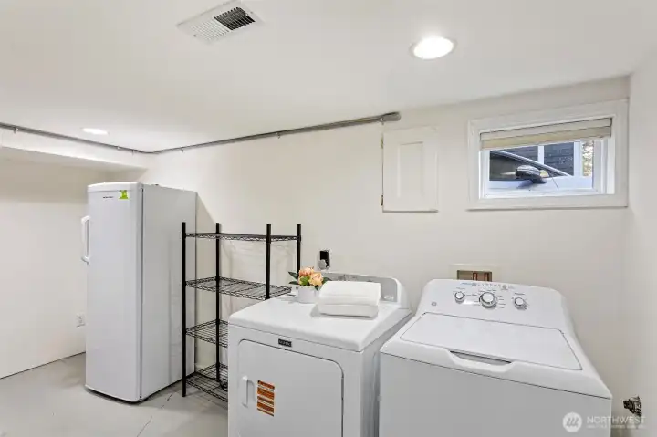 Lower level utility room with W/D, freezer and shelving and access to the furnace and water heater.