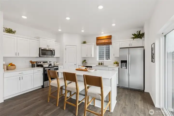 Beautifully open kitchen with stainless steel appliances and large island with breakfast bar. Actual home is under construction. Colors, materials, and features may vary. See site agent for details.