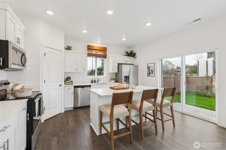 Large open kitchen with breakfast bar. Actual home is under construction and finishes, colors, and materials may vary. See site agent for details.